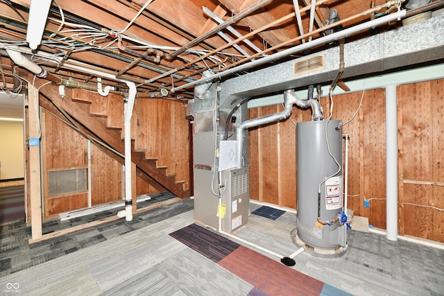 unfinished basement with stairs, gas water heater, visible vents, and heating unit