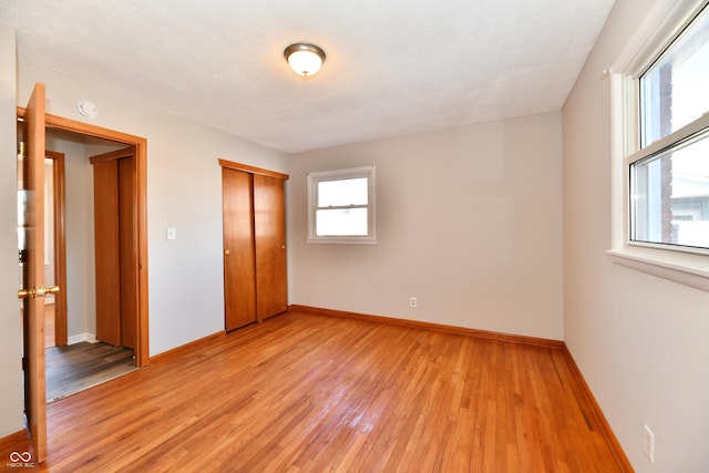 unfurnished bedroom featuring light wood finished floors, a closet, and baseboards