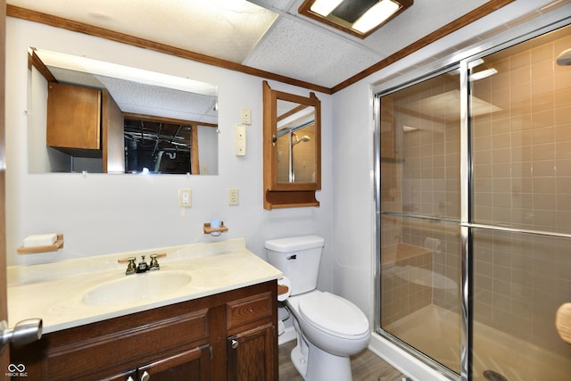 bathroom with a drop ceiling, toilet, vanity, a shower stall, and crown molding