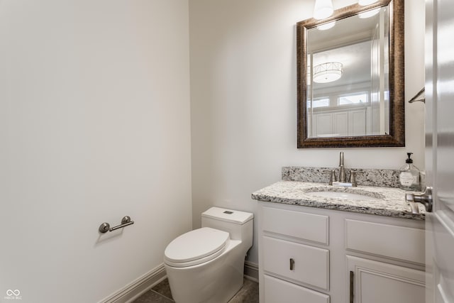 half bath with toilet, tile patterned floors, vanity, and baseboards