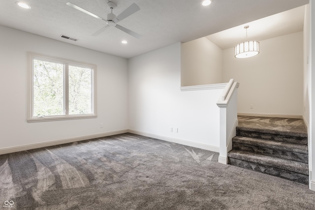 carpeted empty room featuring ceiling fan, recessed lighting, visible vents, baseboards, and stairs