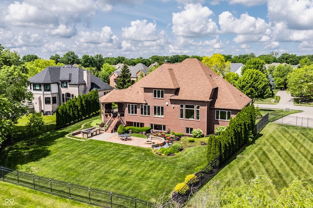 back of house featuring a shingled roof, a lawn, an outdoor fire pit, a patio area, and a fenced backyard