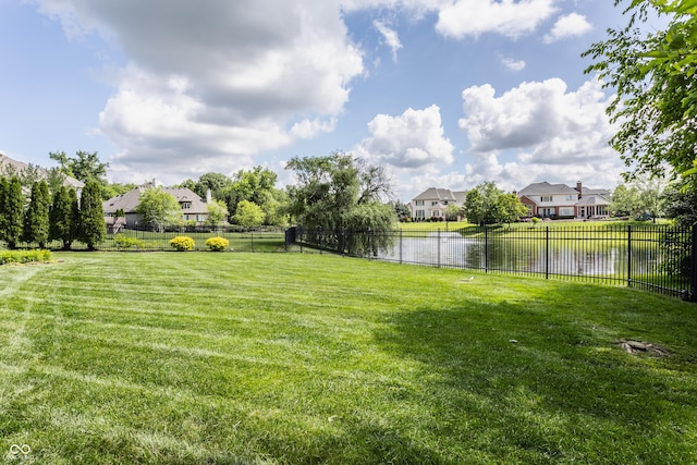 view of yard featuring a water view, a residential view, and fence