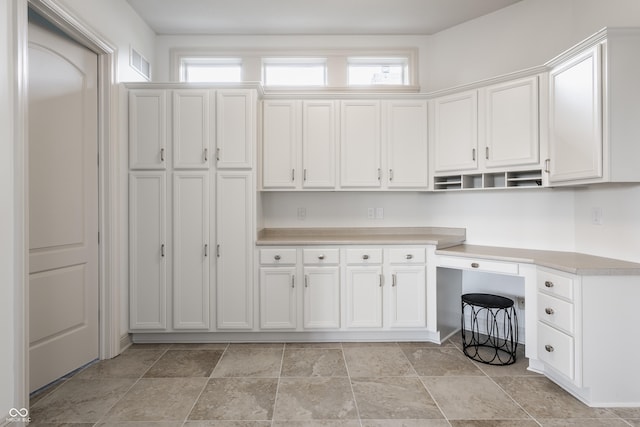 interior space with a wealth of natural light, stone finish floor, and visible vents