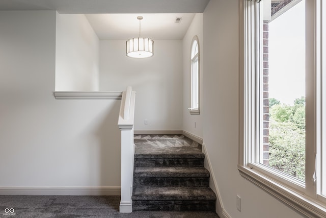 staircase featuring carpet floors, visible vents, and baseboards