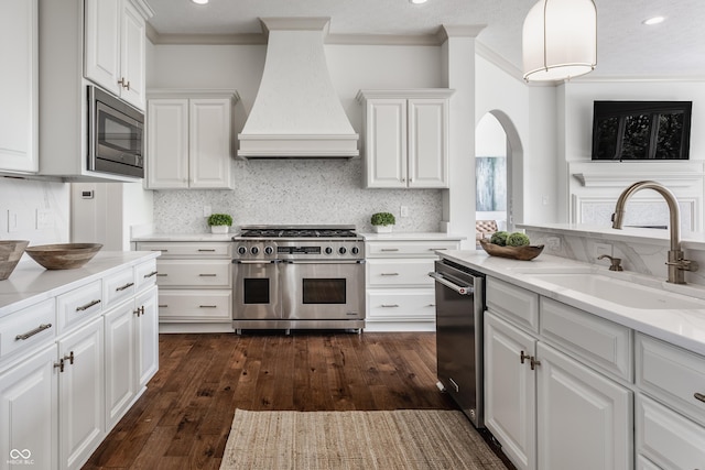 kitchen featuring stainless steel appliances, a sink, white cabinets, light countertops, and custom range hood