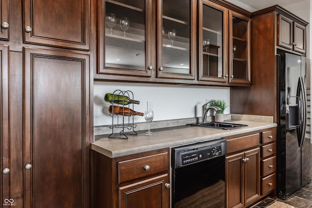 kitchen with black appliances, dark brown cabinets, a sink, and glass insert cabinets