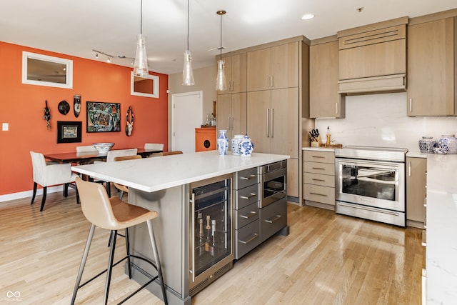 kitchen featuring wine cooler, light wood-style flooring, appliances with stainless steel finishes, and a breakfast bar