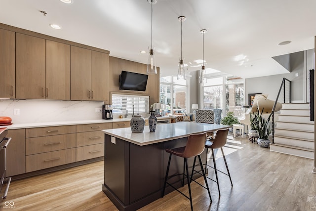 kitchen with light countertops, a kitchen breakfast bar, a healthy amount of sunlight, and light wood-style floors