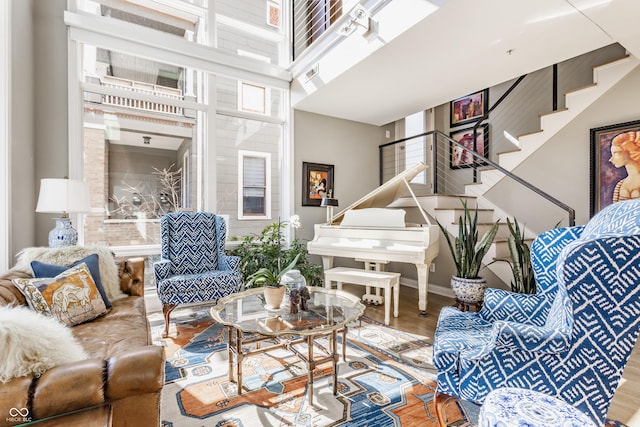 living room featuring a towering ceiling, baseboards, wood finished floors, and stairs