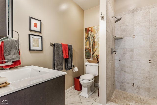 bathroom with baseboards, toilet, tiled shower, tile patterned floors, and vanity