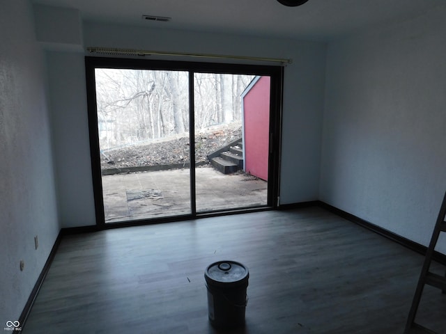 spare room featuring visible vents, baseboards, and wood finished floors