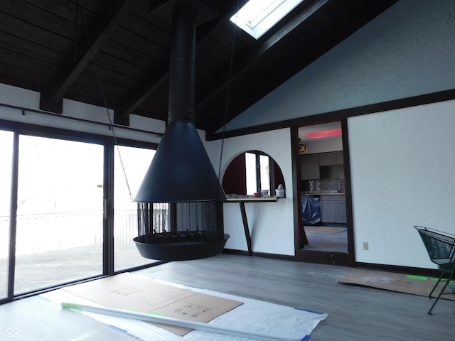 interior space featuring a sink, vaulted ceiling with beams, baseboards, and wood finished floors