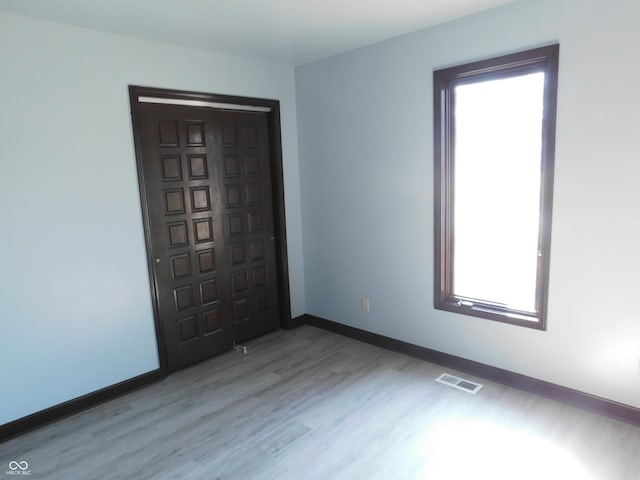 foyer with light wood finished floors, visible vents, and baseboards