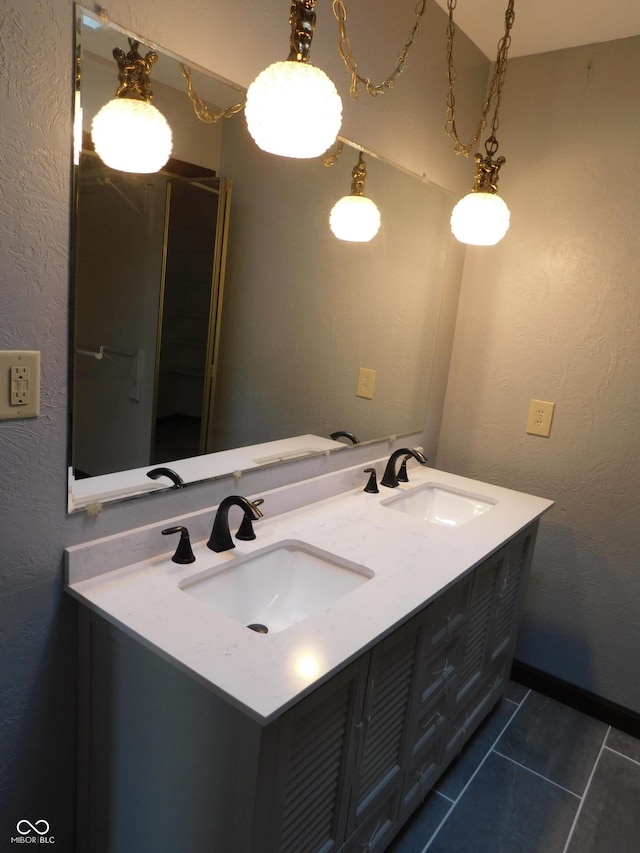 bathroom with a textured wall, double vanity, a sink, and tile patterned floors