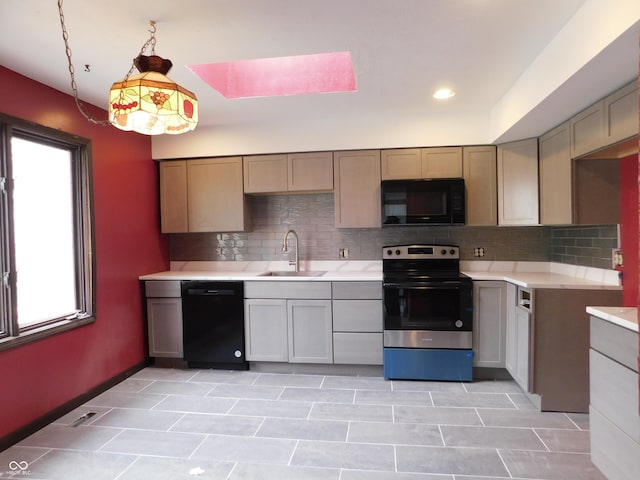 kitchen featuring pendant lighting, light countertops, decorative backsplash, a sink, and black appliances