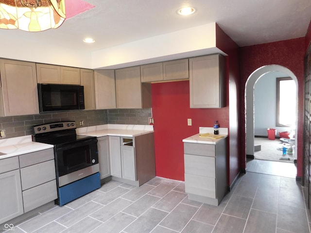 kitchen featuring tasteful backsplash, arched walkways, black microwave, and stainless steel electric stove