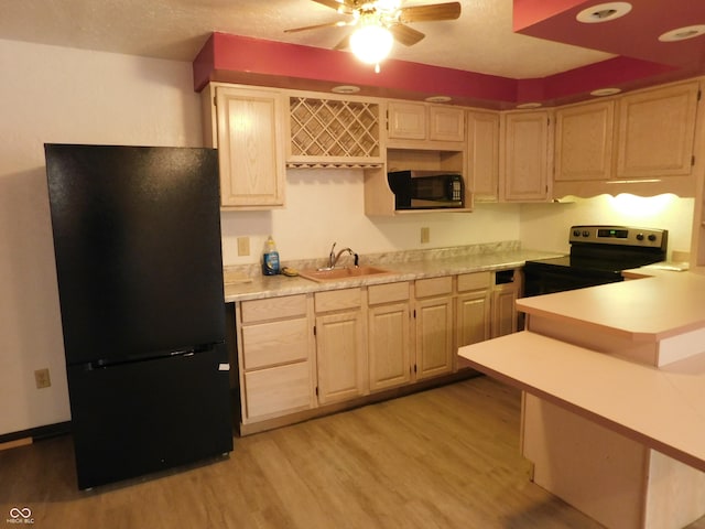 kitchen featuring light wood finished floors, light countertops, freestanding refrigerator, a sink, and stainless steel electric range