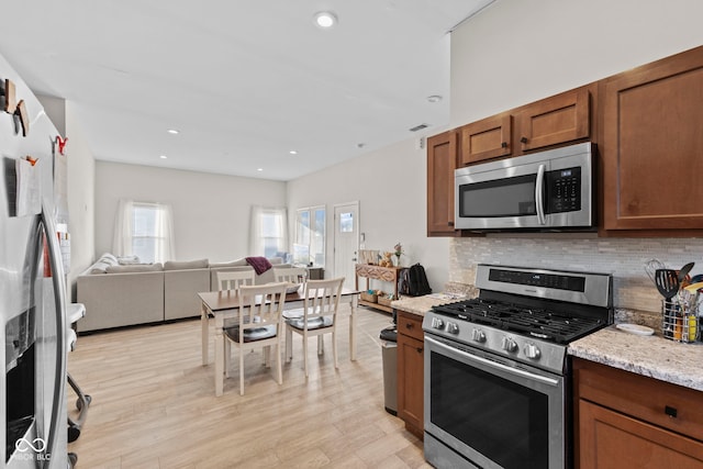 kitchen with recessed lighting, stainless steel appliances, open floor plan, light wood-type flooring, and tasteful backsplash