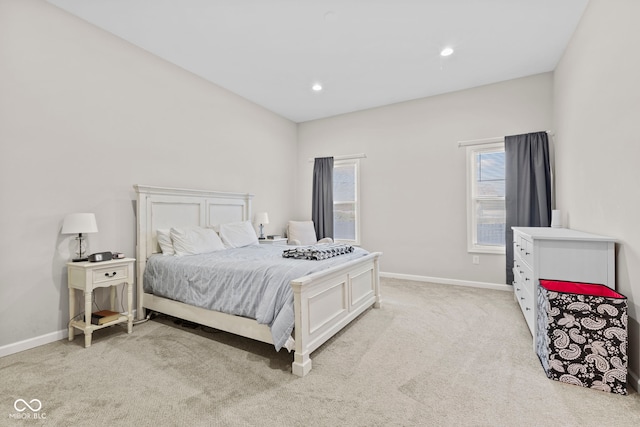 bedroom featuring baseboards, multiple windows, and light colored carpet