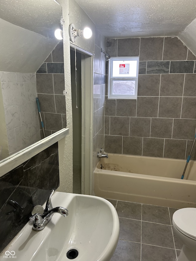 bathroom featuring toilet, vaulted ceiling, a textured ceiling,  shower combination, and tile patterned floors