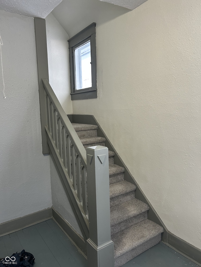 stairway featuring a textured wall and baseboards