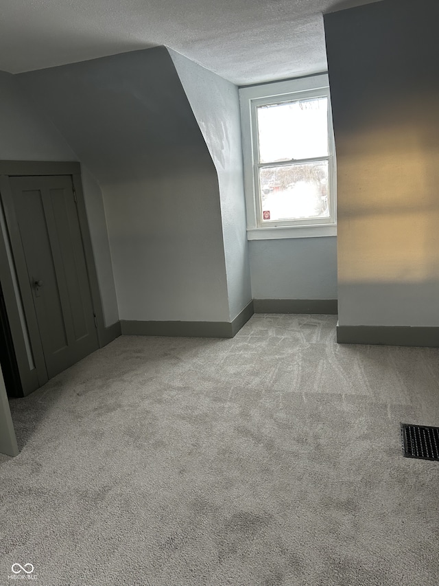 additional living space featuring visible vents, carpet flooring, a textured ceiling, and baseboards