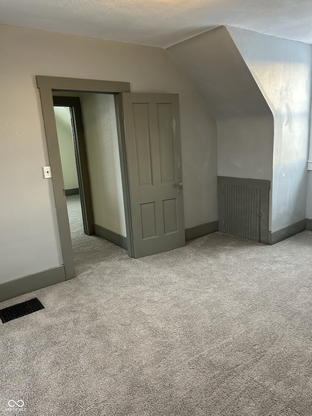 bonus room featuring baseboards, visible vents, vaulted ceiling, and carpet flooring