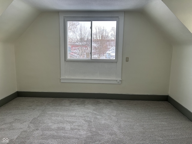 bonus room featuring carpet floors, baseboards, vaulted ceiling, and a textured ceiling