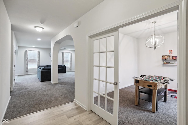 rec room featuring carpet, baseboards, arched walkways, and wood finished floors