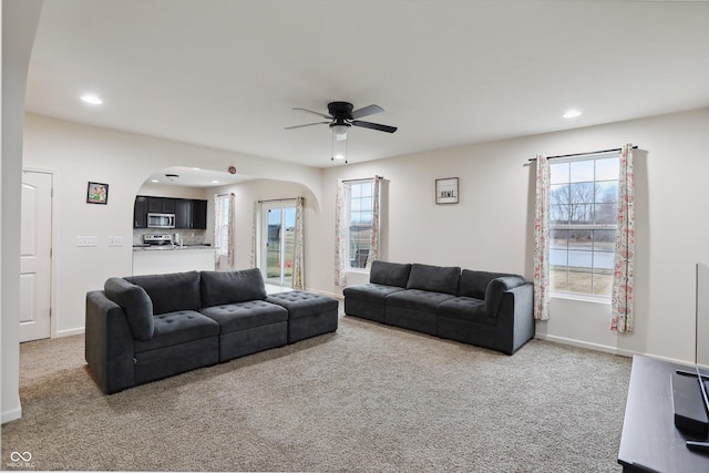 carpeted living area featuring plenty of natural light, arched walkways, baseboards, and recessed lighting