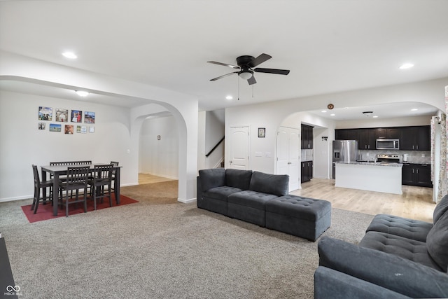 living area with arched walkways, ceiling fan, stairway, and recessed lighting