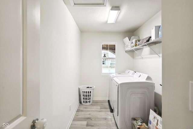 laundry area with laundry area, baseboards, light wood-type flooring, washer and clothes dryer, and attic access