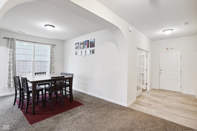 dining space featuring carpet floors, baseboards, visible vents, and arched walkways