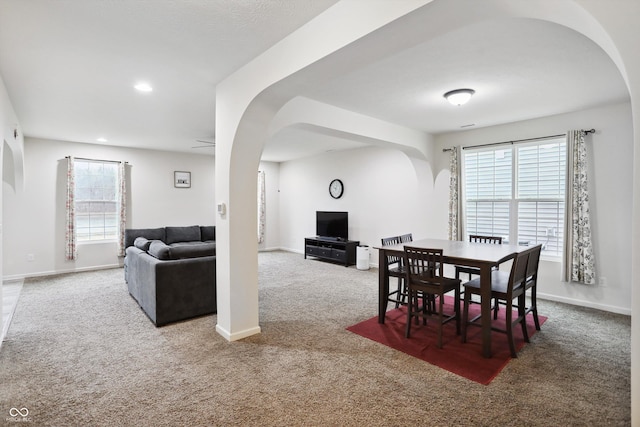 carpeted dining area with arched walkways, baseboards, and recessed lighting