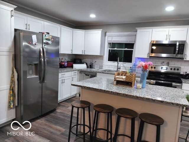 kitchen with stainless steel appliances, dark wood-style flooring, a sink, and white cabinets