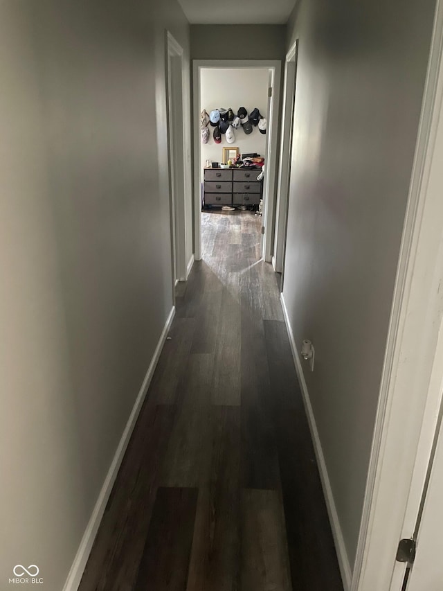 corridor with dark wood-style flooring and baseboards