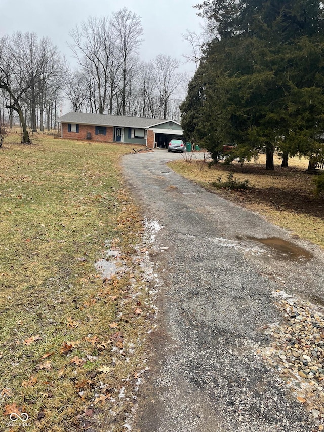 view of front facade featuring a garage, a front yard, brick siding, and driveway