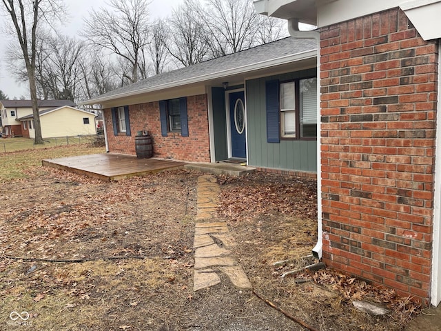 exterior space with brick siding and roof with shingles