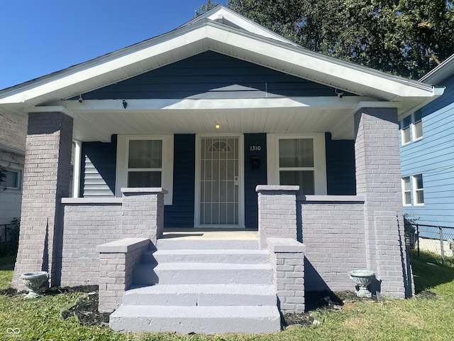 property entrance with a porch and brick siding