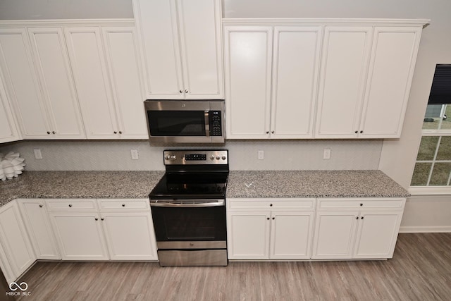 kitchen with light wood-type flooring, appliances with stainless steel finishes, and backsplash