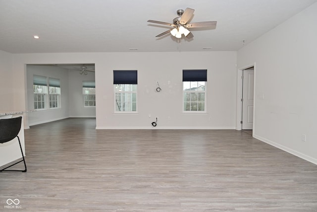 unfurnished living room featuring light wood finished floors, baseboards, a ceiling fan, and recessed lighting