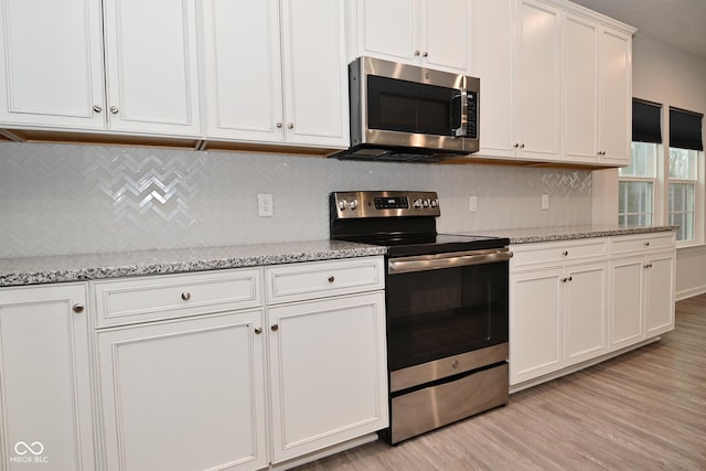 kitchen featuring light stone counters, light wood finished floors, backsplash, appliances with stainless steel finishes, and white cabinets