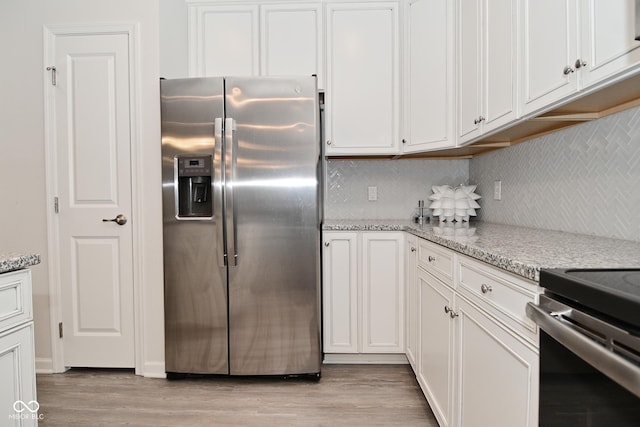 kitchen with stainless steel appliances, backsplash, white cabinets, and light wood-style floors