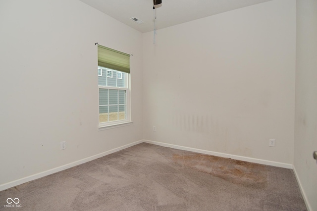 empty room with a ceiling fan, carpet flooring, visible vents, and baseboards