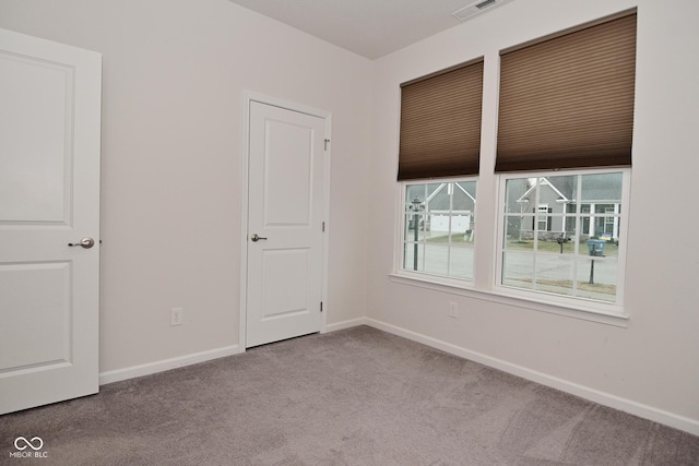 carpeted spare room with visible vents and baseboards