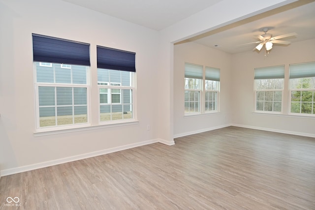 empty room with a healthy amount of sunlight, ceiling fan, baseboards, and wood finished floors