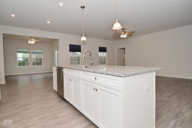 kitchen featuring light wood finished floors, white cabinets, an island with sink, open floor plan, and a sink