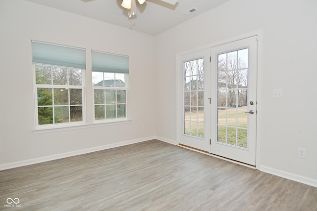 unfurnished room featuring baseboards, plenty of natural light, visible vents, and wood finished floors