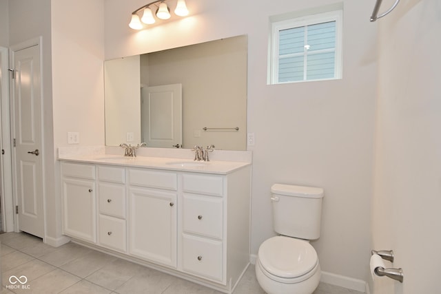 full bathroom with double vanity, tile patterned flooring, a sink, and toilet